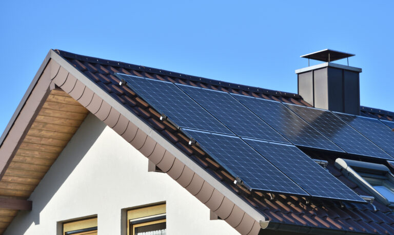 Panele słoneczne montowane na dachu domu, na błękitnym niebie